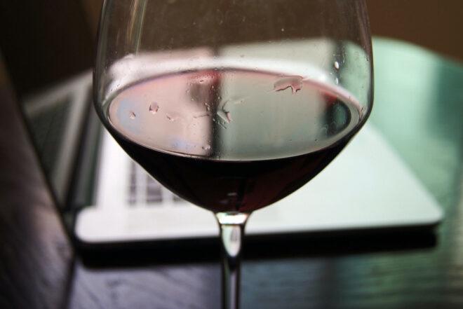 glass of red wine in front of a laptop