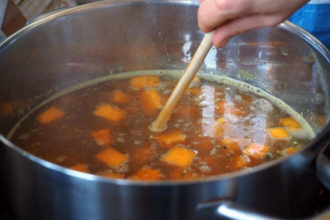 person making broth with orange vegetables