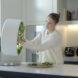 person picking fresh greens from a round indoor garden