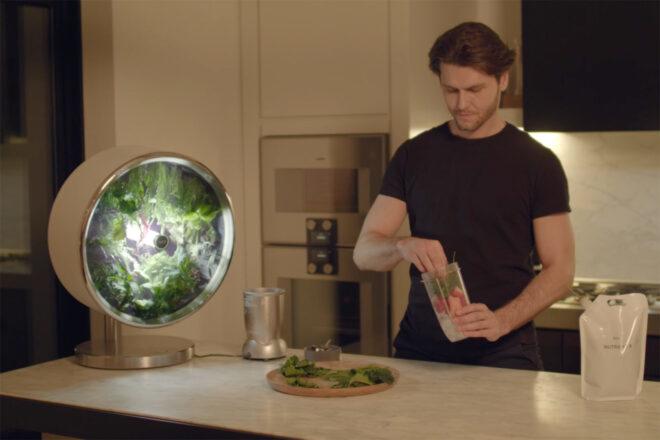 person grabbing fresh greens from a round indoor garden to add to a smoothie