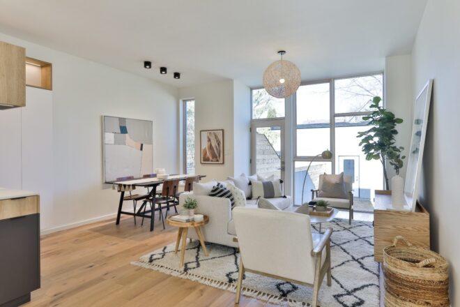 dining table behind a white sofa in white room with large glass window