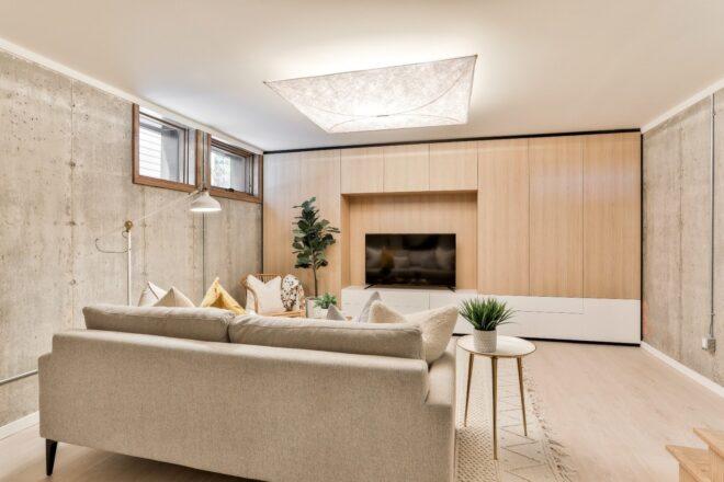 light gray sofa near wood-paneled wall with a flat-screen TV