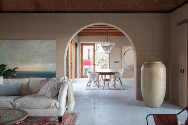 a living room with a white couch and arched entranceway that leads into an area with a dining table and chairs