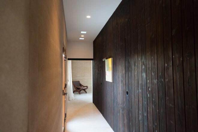 a hallway with one side covered in dark wood paneling