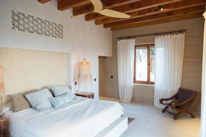 a white bedroom with a window surrounded by white curtains