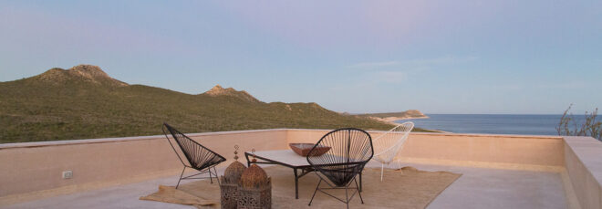 a patio area with table and chairs overlooking a mountainous landscape