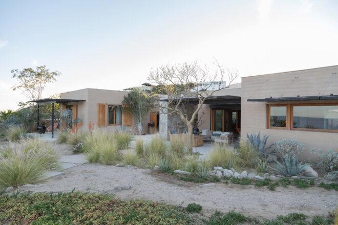 another angle of a stone and rammed earth home surrounded by desert landscape