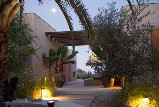 a stone and rammed earth home surrounded by foliage and lights