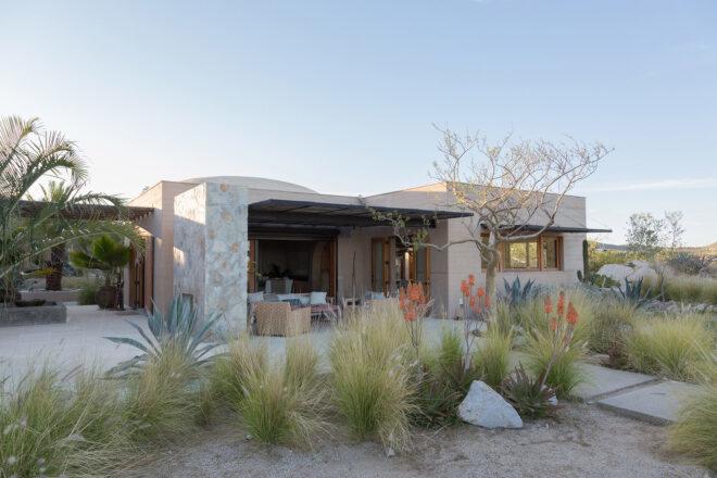a stone and rammed earth home surrounded by desert landscape