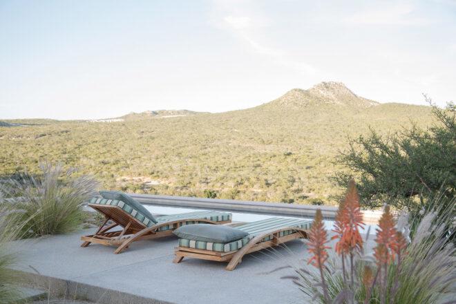 two pool chairs on a patio area overlooking a mountainous landscape