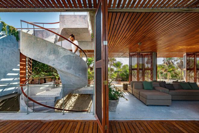 to the left, a spiral staircase with a person walking up it. to the right, a seating area in a structure with wood ceilings and accents