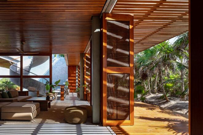 a living area with windows and wood accents and an open door leading outside to a forested area
