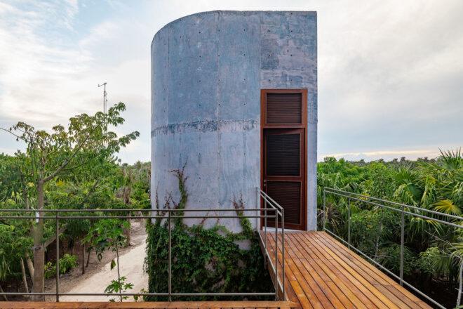 a wood walkway leading to an attached tower of the villa.