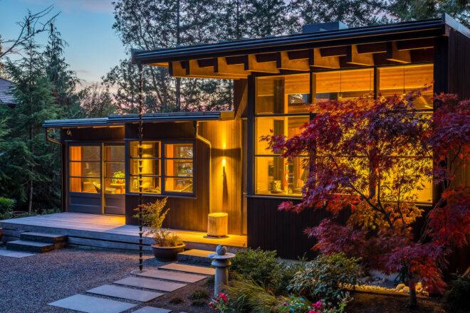 a single-story home lit up from the inside and surrounded by nature