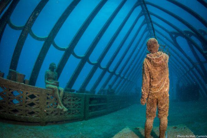 statues of people relaxing in an underwater greenhouse