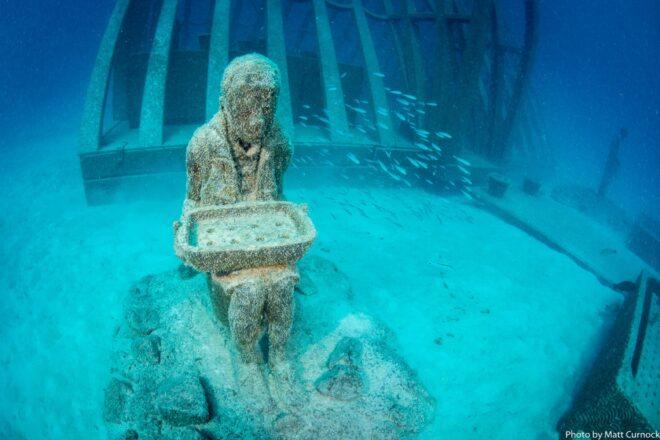 statue of person holding large rectangular planter