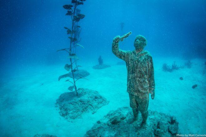 underwater statue of child holding a fish