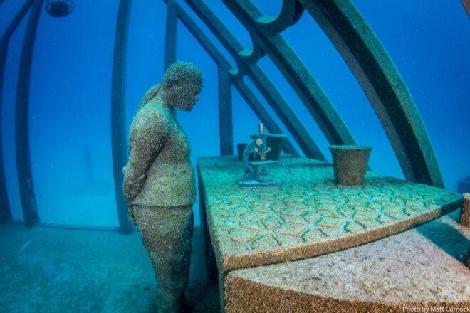 statue of person looking at a microscope