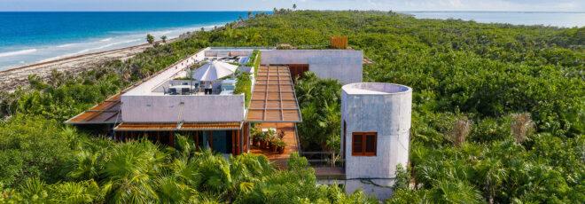 the entire villa, surrounded by greenery, with an ocean to the left