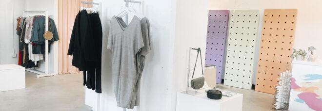 gray dresses, black dresses, and a gray purse all hanging from racks on a wall