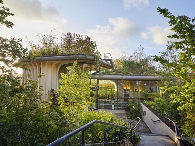 wood-framed building with glass walls and lush green roofs