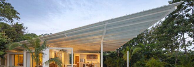 a villa with an angular white roof, lit up from the inside