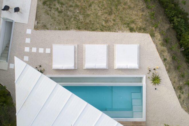 a bird's-eye view of the home, showcasing the angular white roof and pool