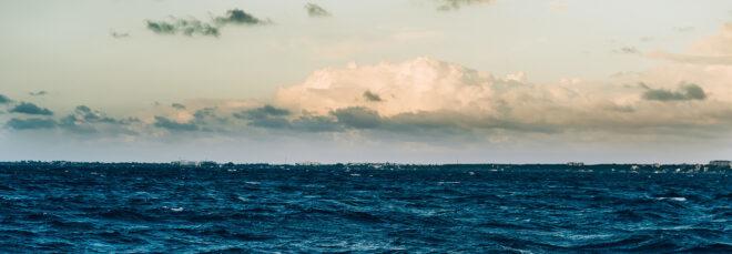 a deep blue ocean against a cloudy sky