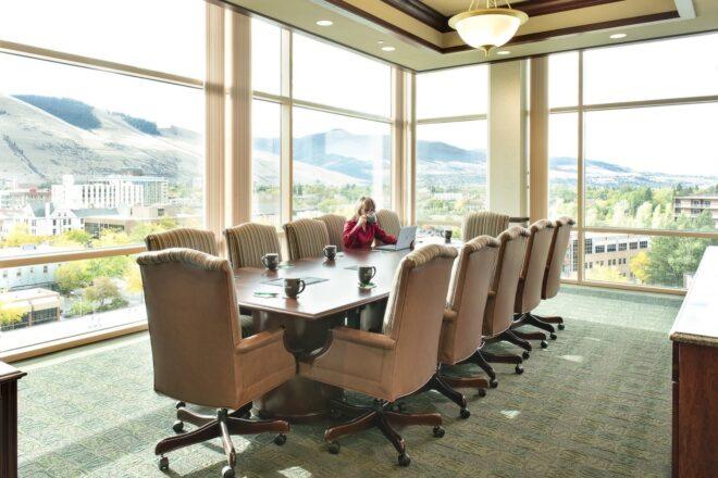 large meeting table with tan chairs in office with glass walls