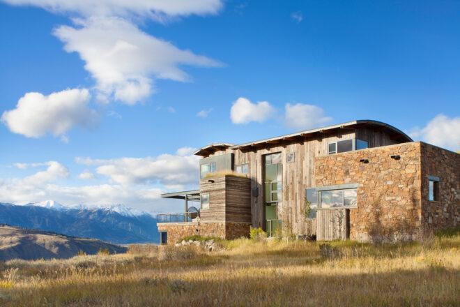 wood and stone home with curved roof