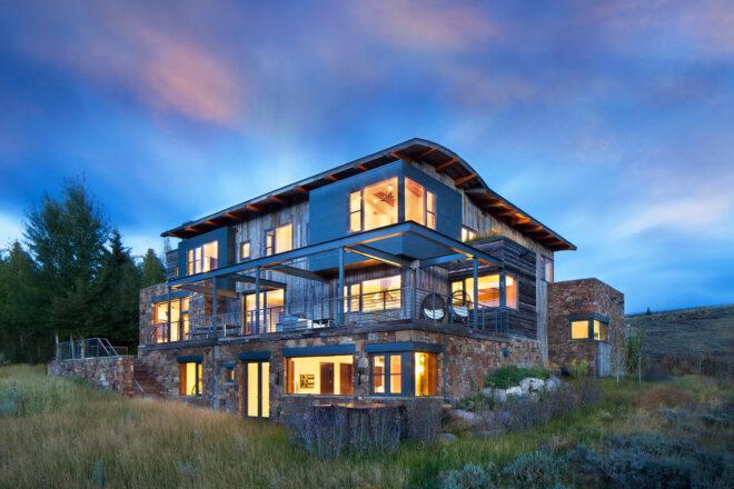 three-story home with wood and stone exterior at dusk