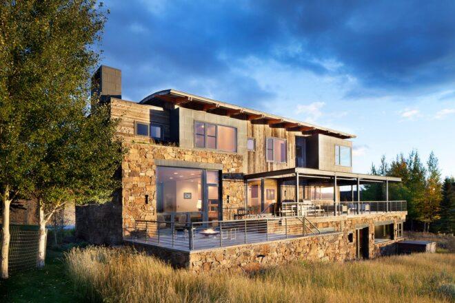 wood and stone home with curved roof and large back deck