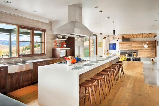 long white island with several wood bar stools