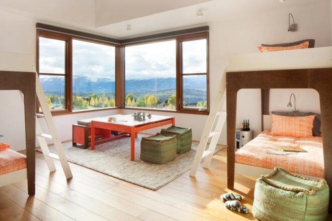 Room with two sets of bunk beds and a large corner window revealing mountain views