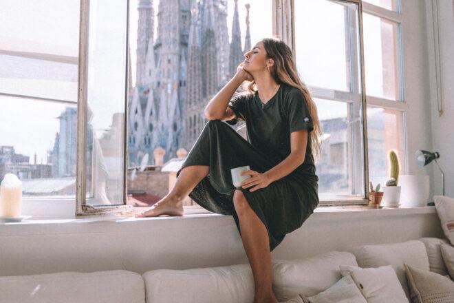 person wearing maxi-length T-shirt dress while sitting on a window sill