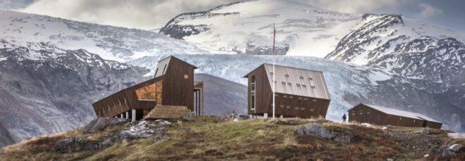 two angular wood cabins with mountains in the background