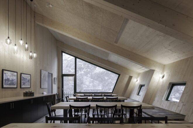 dining tables facing a large, angular window