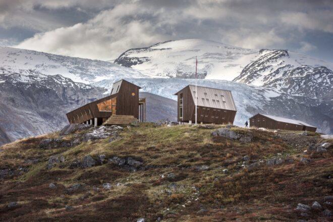 two angular wood cabins with mountains in the background