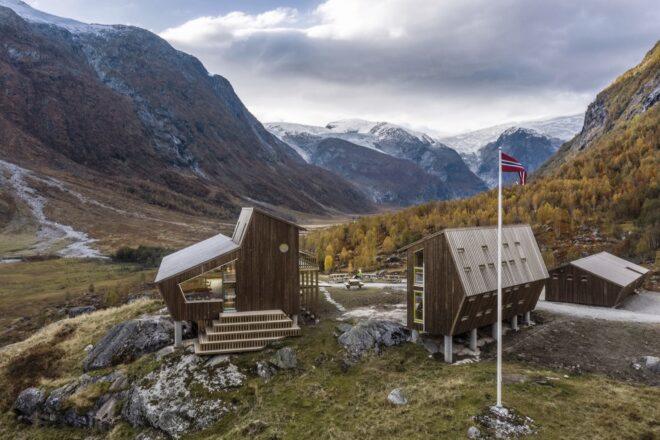 two angular wood cabins surrounded by mountains