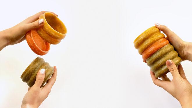 two sets on hands on the left and right, each holding mugs in various shades of orange