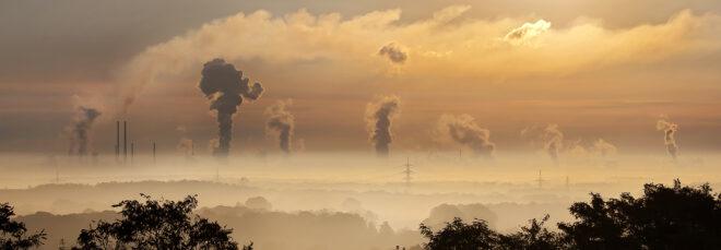 a landscape of hazy air with plumes of smoke emerging in the background