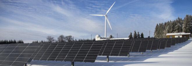 an array of solar panels with a windmill in the background