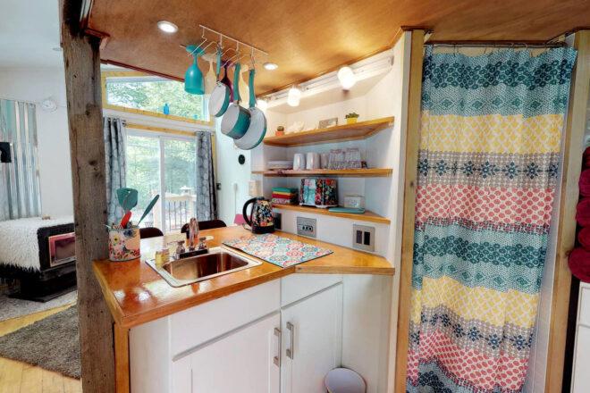 small kitchen with white cabinets and wood counters and hanging teal pots and pans