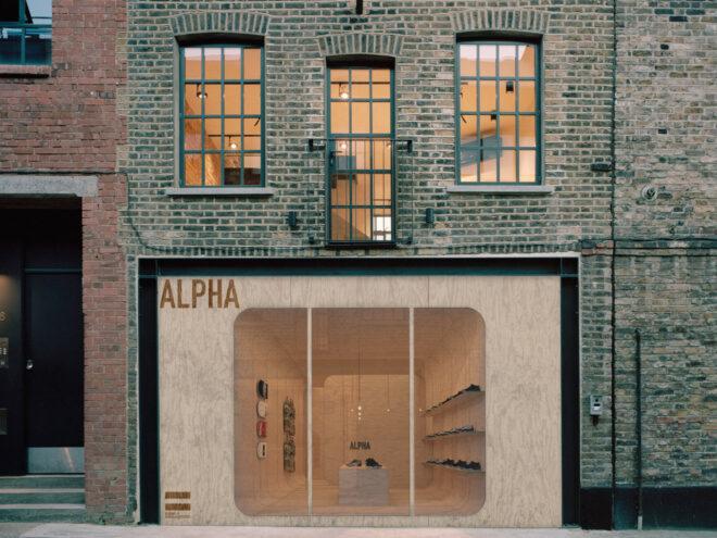 plywood cube building on the ground floor of a larger brick building