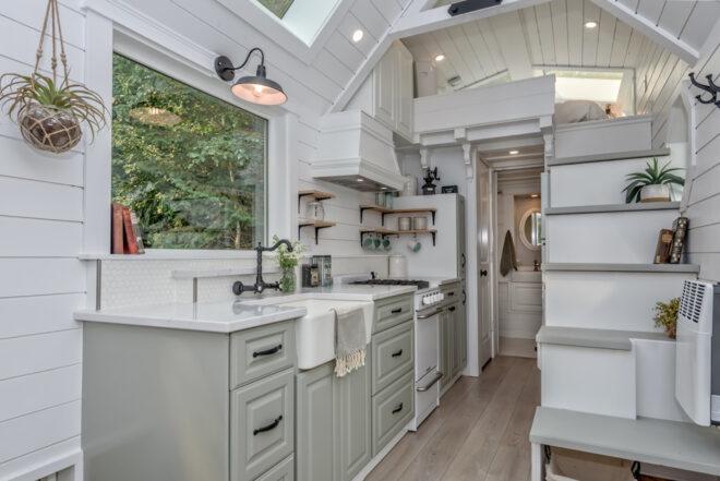 a kitchen inside the tiny home, featuring a large window above the sink