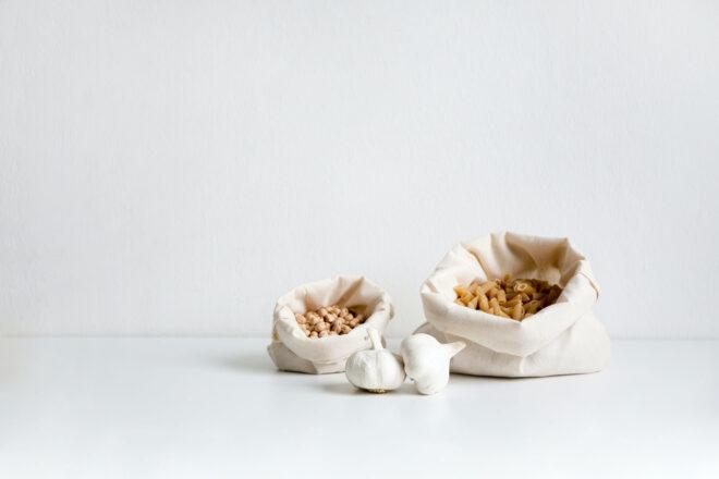 reusable produce bags filled with pasta on a white background