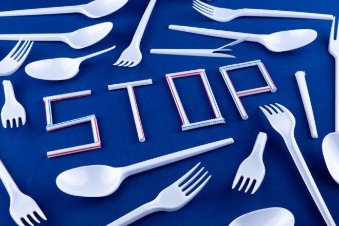 plastic eating utensils surrounding plastic straws arranged to spell out the word "STOP"