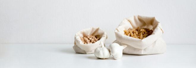 reusable produce bags filled with pasta on a white background