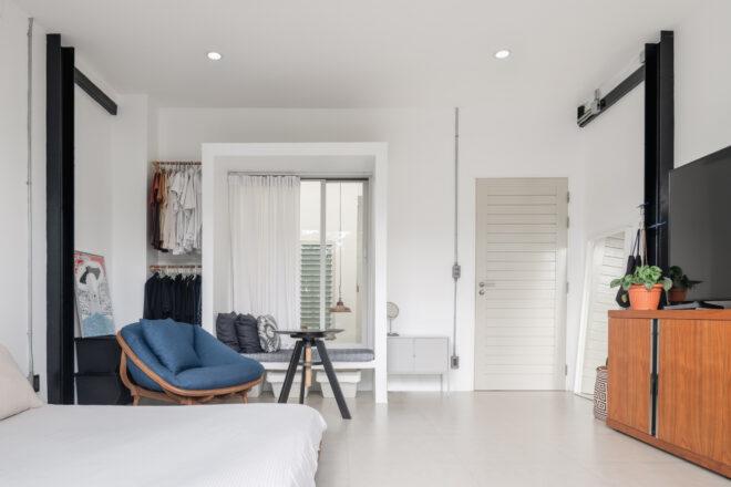 large bed across from a TV and a blue chair near a window seat