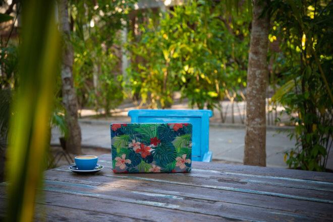 laptop with floral case on an outdoor table surrounded by trees